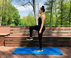 Woman performing standing march on exercise mat