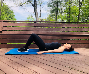 Woman performing pelvic tilt on exercise mat