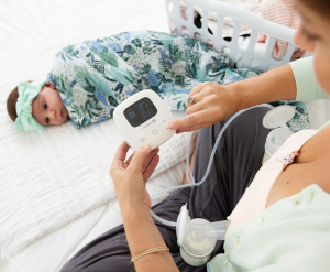 Women breast pumping on bed with Cimilre P1, baby and basket in background