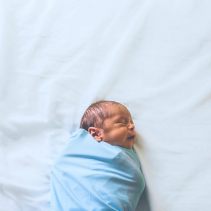 Newborn baby swaddled on bed sleeping